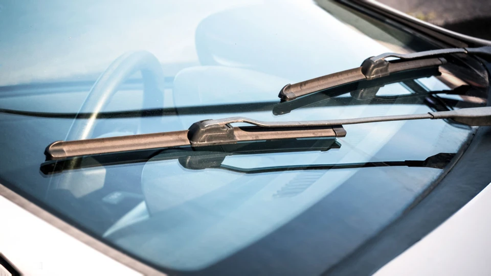 Deux vrais mécaniciens changeant le pare-brise brisé de la voiture noire dans l'atelier de réparation automatique