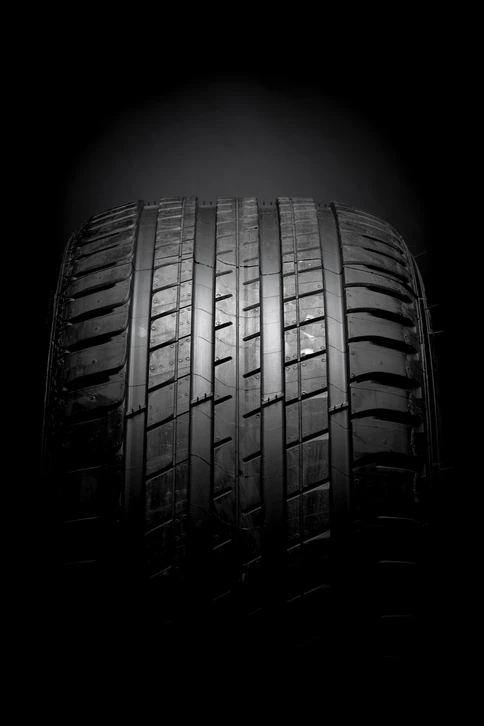 Traces de pneumatiques courbées formant un motif ondulant sur fond blanc, créant un effet visuel dynamique de mouvement et de vitesse