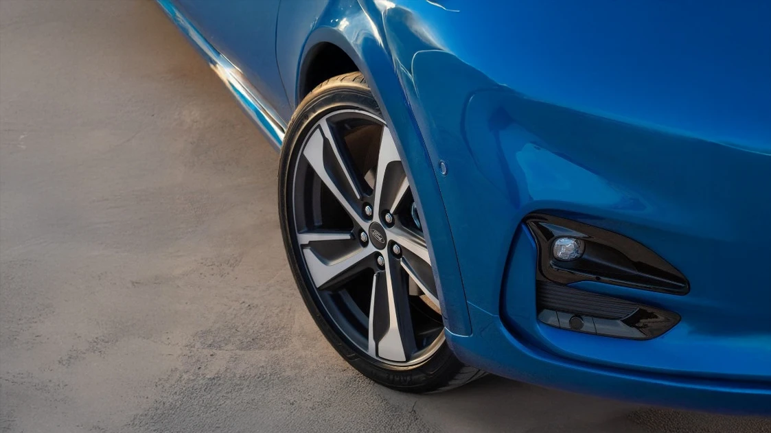 Mécanicien en salopette grise examine attentivement un pneu hiver dans un garage automobile